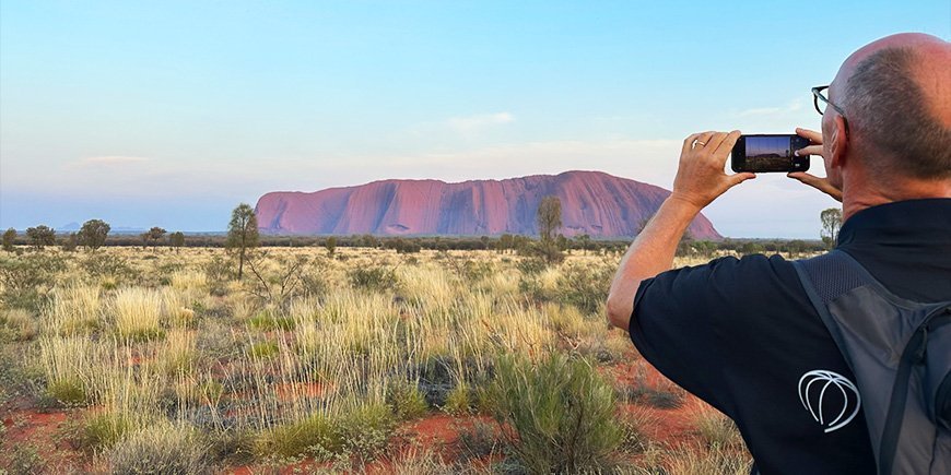 Man takes mobile phone photo of Uluru in Australia
